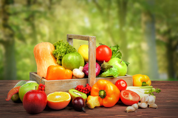 Fresh vegetables and fruits on wooden table against nature background