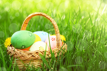 Wicker basket with Easter eggs on green grass