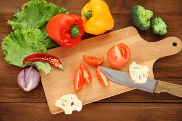 Fresh vegetables and knife with cutting board, top view