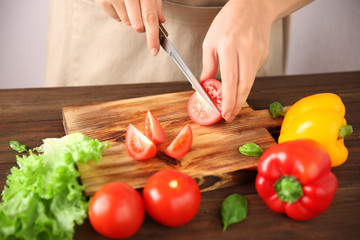 Woman chopping fresh vegetables on cutting board