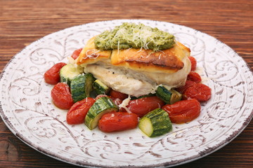 Tasty baked chicken breasts which basil pesto sauce, tomatoes, and cheese. Healthy eating concept.