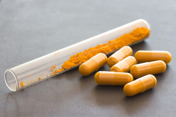 Turmeric powder  in tube and herbal Turmeric capsule on black ba