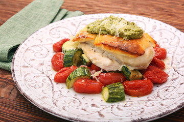 Tasty baked chicken breasts which basil pesto sauce, tomatoes, and cheese. Healthy eating concept.