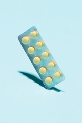 Yellow oral contraceptive pill strips on blue background with sh