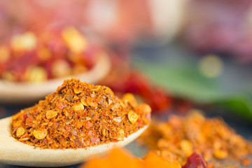 Herbs and spices,chili pepper powder in wooden spoon over black