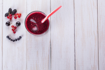 Berry smoothie on the white wooden background. Smile from berries. Diet food concept. Copyspace. Fresh berries, blueberries, blackberries. waffle with smiley face. Top view, flat lay.