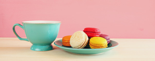 Cup of coffee and colorful macaron on wooden table