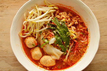 large noodle with pork ball in tom yum spicy soup topping fresh bean sprout on bowl