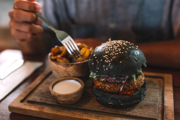 Black hamburger with potatoes and white sauce on the table, indonesia, Bali