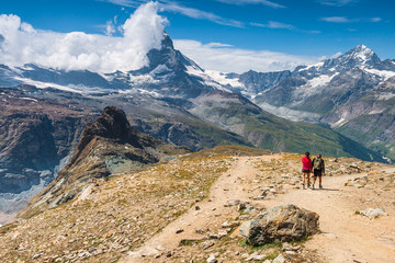 Fototapeta na wymiar Hikers walking on spectacular mountain scenery, Matterhorn in background, Alps, Switzerland.