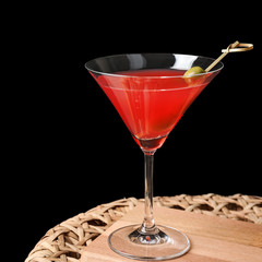 Pink cocktail on wicker table and black background
