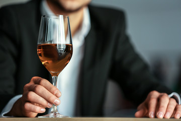 Man holding glass with wine on blurred background