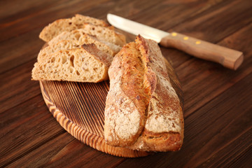 Sliced bread with knife on wooden background
