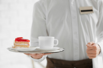 Waiter in white shirt bringing the ordered dessert and cup of coffee in a cafe, close up