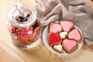 Valentine's day cookies in glass jar and on plate against wooden background
