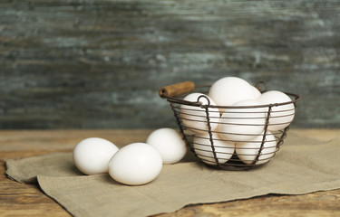 Raw eggs in basket on wooden table