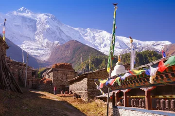 Fotobehang Upper Pisang village, buddhist praying wall with wheels and flags and North Face of Annapurna II mountain summit on background, Annapurna Circuit Trek, Himalaya, Nepal, Asia.  © olmoroz