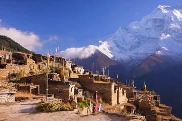Traditional nepalese village on Pisang region with buddhist praying flags and North Face of Annapurna II mountain summit on background, Annapurna Circuit Trek, Himalaya, Nepal, Asia. horizontal view