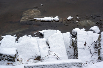 Multiple snow covered rocks next to water