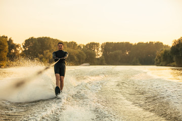 Male water skiing behind a boat on lake