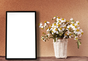 Blank white frame mockup with chamomile flowers in bamboo basket on wooden table on vintage tone. Poster product design styled mock-up.
