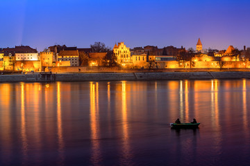 Panorama of Torun Old Town at night with colorful reflection in Vistula river. Poland, Europe.