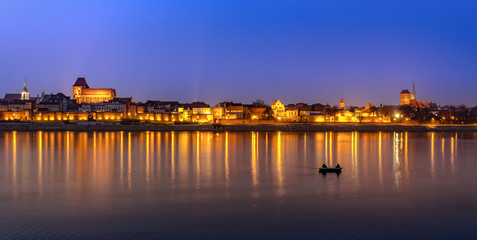 Panoramic view of Torun. Medieval Old Town at night reflected in Vistula river, Poland. Europe.