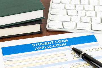 Student loan application form with pen, keyboard, and text book