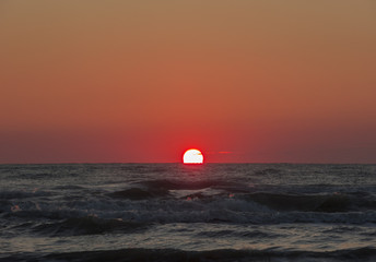 Fiery sunrise at Italian beach. Summer season. Emilia Romagna region. Adriatic sea. Italy