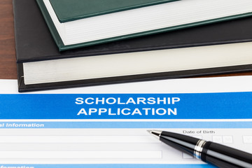 Scholarship application form with pen and text book
