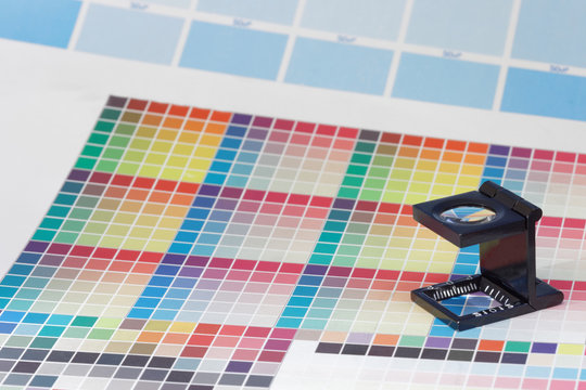 Magnifier or printer's loupe sits on a colorful CMYK test sheet