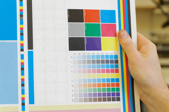 Hand holding a colorful test print for inspection