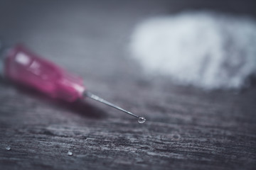 Drug syringe and cooked heroin on wood table