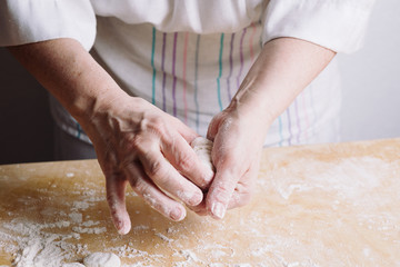 Close-up view of two woman's hands making meat dumplings.