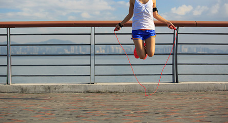 young fitness woman jumping rope at seaside