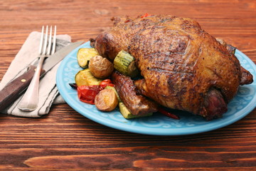 Festive roast duck with vegetables on plate on wooden table