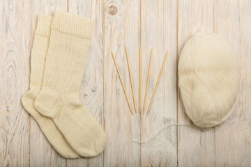 Fototapeta na wymiar Knitted of white yarn socks, yarn and knitting needles on a ligh