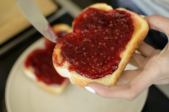 Person Holding Toasted Sliced Bread Spreading Jam 