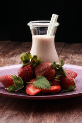 Strawberry smoothie or milkshake in jar on black rustic background, healthy food for breakfast and snack