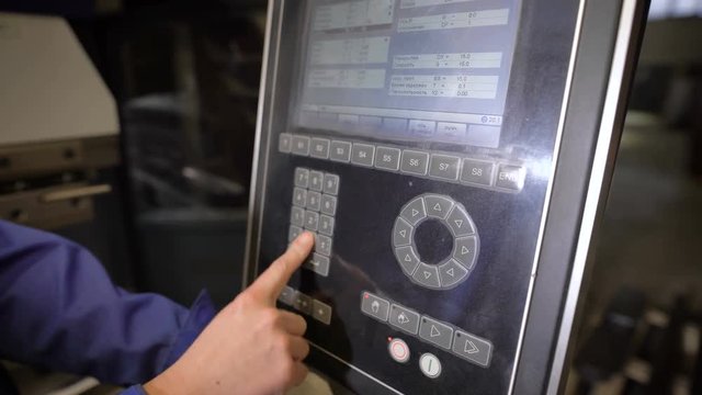 The worker presses buttons of the panel of the machine tool with numerical programmed control. The engineer configures a program for operation of the machine.