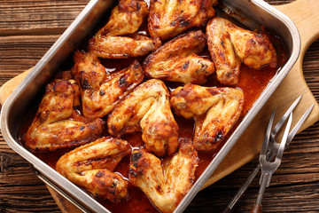 Chicken wings baked in a pan on wooden background