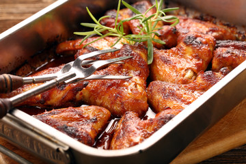 Chicken wings baked in a pan on wooden background