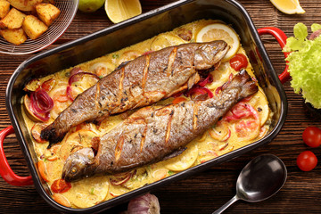 Baked fish with lemon sauce and vegetables in a pan