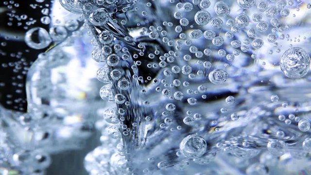 Air bubbels in mineral water glass with ice cubes, closeup.