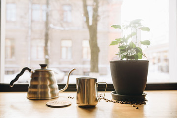The window and windowsill with pitcher, coffee, green flower in daylight mear 