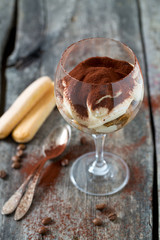 tiramisu in a vine glass on wooden surface