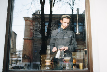 Obraz na płótnie Canvas Man barista in window with glass pitcher