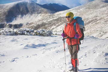 Girl with backpack walking on snow in the mountains.