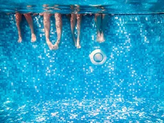 Foto op Canvas Children's and adults legs underwater in swimming pool © k8most