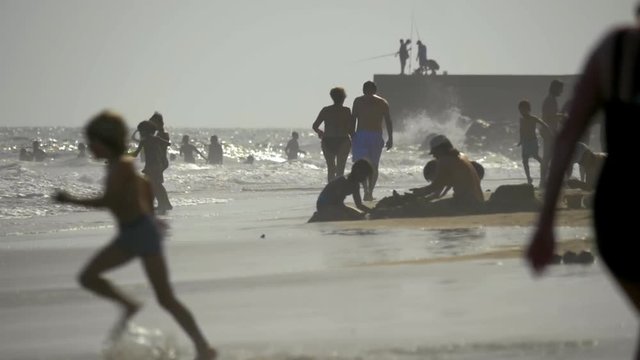 GRAN CANARIA, CANARY ISLANDS - AUGUST 02, 2016: Adults abd children spending vacation on the coast. People bathing, walking, making sand castles and fishing